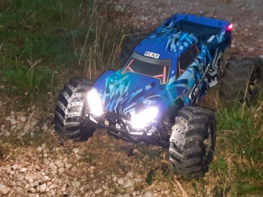 Blaues ferngesteuertes Monstertruck-Modell auf unebenem Gelände.
