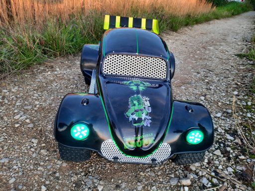 Schwarzes beliebtes Spielzeugauto mit grünen Lichtern, auf einem Kiesweg platziert.