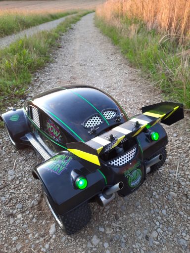 Schwarzes Modellauto mit grünen und gelben Akzenten auf einem Kiesweg.